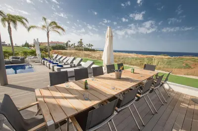 a long wooden table with chairs and an umbrella at Villa Chana in Protaras