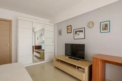 a living room with a television and a table at Lovely Bedroom in shared apartment Oroklini in Voroklini