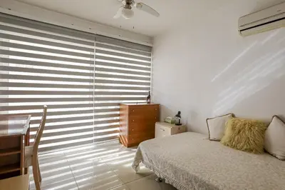 a bedroom with a bed and a table and a window at Lovely Bedroom in shared apartment Oroklini in Voroklini