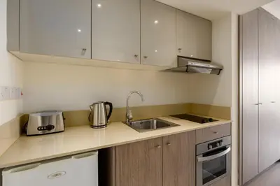 a small kitchen with white cabinets and a sink at Melpo Antia Hotel & Suites in Ayia Napa
