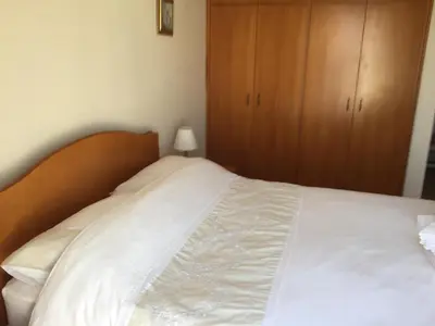 a white bed with a wooden headboard in a bedroom at 2 Bed Flat - Sleeps 4 - Pool - Parking - Wifi in Xylophaghou