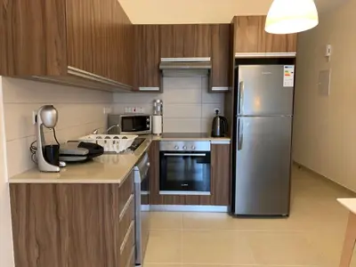 a kitchen with stainless steel appliances and wooden cabinets at Mythical Sands new Luxury Apartment in Paralimni