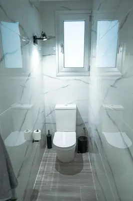 a white bathroom with a toilet and a window at Andreotis Villas in Protaras