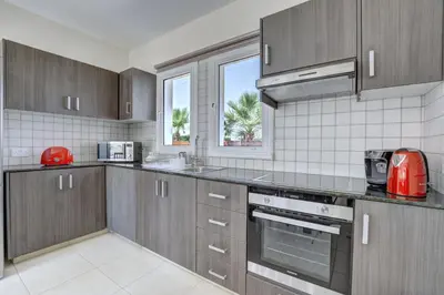 a kitchen with wooden cabinets and a red appliance at Villa Nissi Gold in Ayia Napa