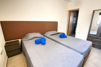 two beds in a bedroom with blue slippers at Villa Nissi Gold in Ayia Napa