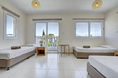 a bedroom with three beds and a balcony at Nissi Palms Villa in Ayia Napa