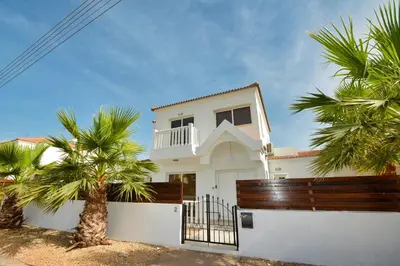 a white house with palm trees in front of it at Nissi Palms Villa in Ayia Napa