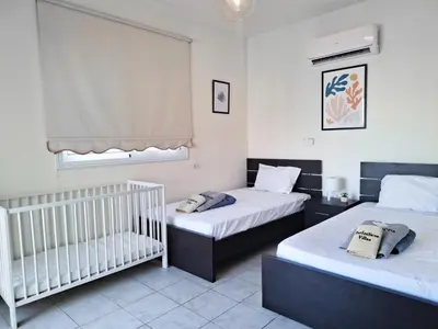 a room with two beds and a crib in it at Villa Lynn Chill Out Seaview in Ayia Napa