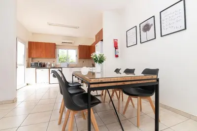 a dining room with a wooden table and black chairs at Konnos Villa Ekaterina in Protaras
