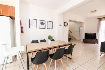 a dining room with a wooden table and chairs at Konnos Villa Ekaterina in Protaras