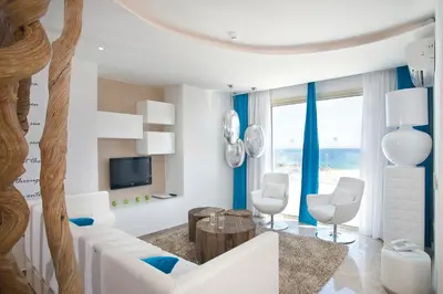 a living room with white furniture and blue curtains at Althea Kalamies Luxury Villas in Protaras