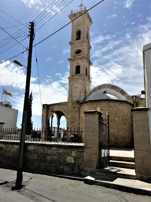 a building with a clock tower with a fence at Lemon Tree Courtyard in Larnaka