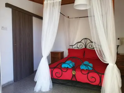 a bedroom with a red bed with curtains at Lemon Tree Courtyard in Larnaka