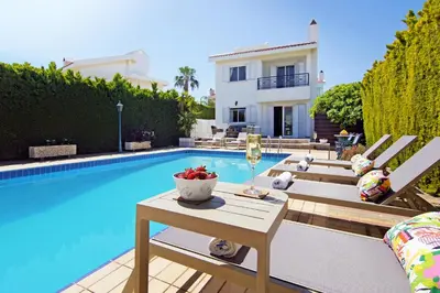 a villa with a pool and a table with a glass of wine at Villa Aleta in Protaras