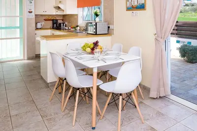 a kitchen with a white table and white chairs at Villa Aleta in Protaras