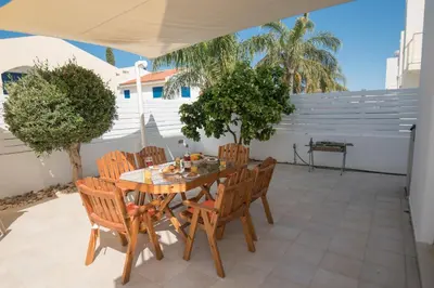 a wooden table and chairs on a patio at Villa Pomelo in Protaras