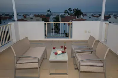 a balcony with three chairs and a table with drinks on it at Villa Pomelo in Protaras