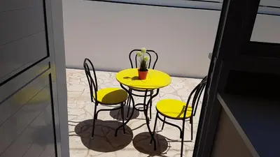 a yellow table with four chairs and a vase on it at ZORBAS No 3 in Larnaka