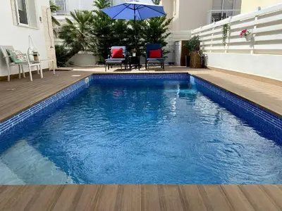 a swimming pool with a table and chairs and an umbrella at Kalimera Villa Protaras in Protaras