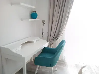 a white desk with a blue chair next to a window at Aquamarine in Voroklini