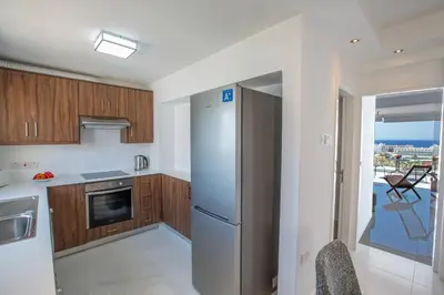 a kitchen with wooden cabinets and a stainless steel refrigerator at Rio Luxury Apartment in Ayia Napa