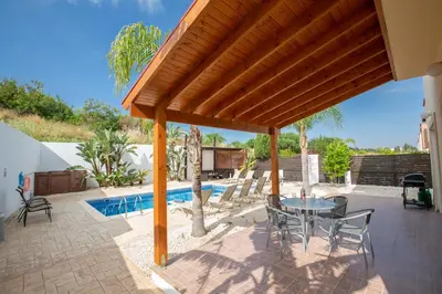 a patio with a table and chairs and a pool at Villa To Perivoli in Protaras