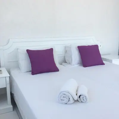 a white bed with purple pillows and towels on it at Aphentrika Apartments in Protaras