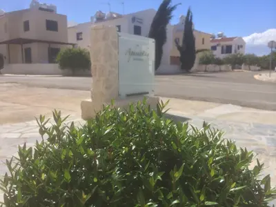a bush in front of a sign in a parking lot at Aphentrika Apartments in Protaras