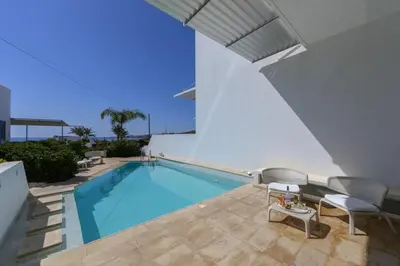 a swimming pool with chairs and a table next to a building at Protaras Villa Kalena Seafront in Protaras