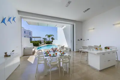a dining room with a table and chairs and a pool at Protaras Villa Kalena Seafront in Protaras