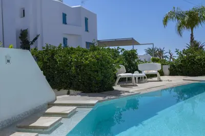 a swimming pool with two chairs and a building at Protaras Villa Kalena Seafront in Protaras