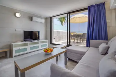 a living room with a couch and a tv and a table at Gevoni Deluxe Suites in Ayia Napa