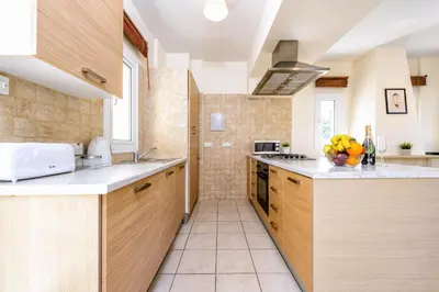 a kitchen with wooden cabinets and a counter top at Villa Di Gio in Paralimni