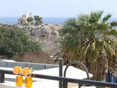 a table with two glasses on top of a balcony with palm trees at Ocean View sunny retreat in Protaras