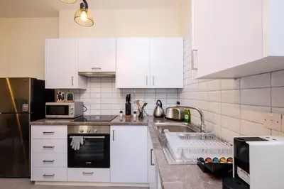 a white kitchen with a sink and a refrigerator at The Joy - Centre One Bedroom Flat in Larnaka