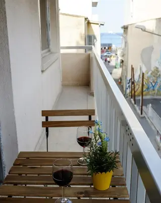 a table with two glasses of wine and a plant on a balcony at The Joy - Centre One Bedroom Flat in Larnaka