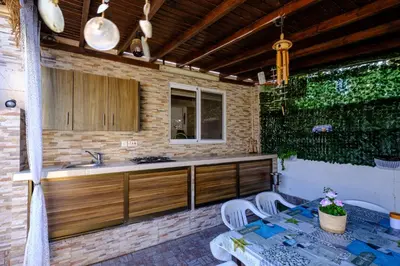 a outdoor kitchen with a sink and two chairs at Demetris apartment in Meneou