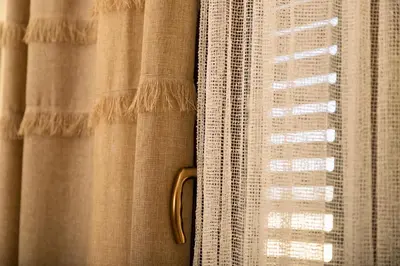 a window with curtains with a gold handle at Salamiou Stone House in Paphos City