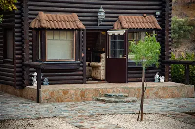 a cabin with a door and a tree in front of it at *2 bdr log house /mountains/Queen bed/fireplace in Gourri