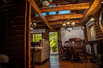 a dining room with a table and chairs at *2 bdr log house /mountains/Queen bed/fireplace in Gourri
