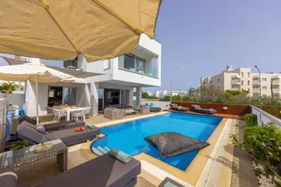 a house with a swimming pool with chairs and an umbrella at Fig Tree Bay Residences 5 in Protaras