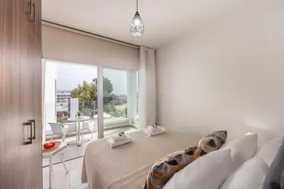 a bedroom with a bed and a large window at Fig Tree Bay Residences 5 in Protaras