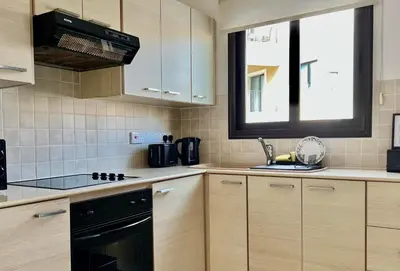 a kitchen with wooden cabinets and a black stove top oven at Seana Villa Protaras in Paralimni