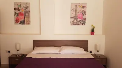 a bedroom with a bed with two tables and two pictures at ZORBAS No 2 in Larnaka