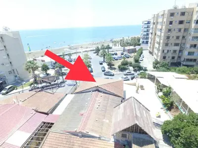 a red arrow on top of a building next to a beach at ZORBAS No 2 in Larnaka