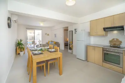 a kitchen and living room with a wooden table and chairs at Emily apartment in Paralimni