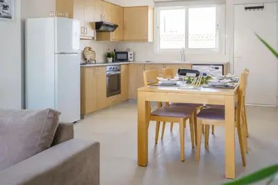 a kitchen with a table and chairs and a white refrigerator at Emily apartment in Paralimni