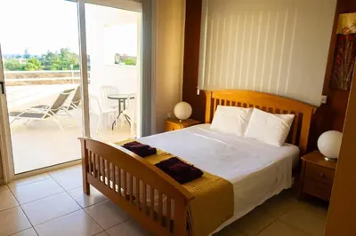 a bedroom with a bed and a balcony with a table at Nissi Elena -Sunshine Apt in Ayia Napa