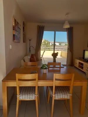 a living room with a wooden table and chairs at Nissi Elena -Sunshine Apt in Ayia Napa