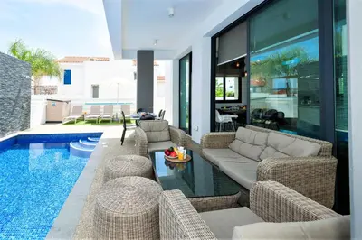 a living room with a couch and chairs next to a pool at Villa Mirella in Protaras